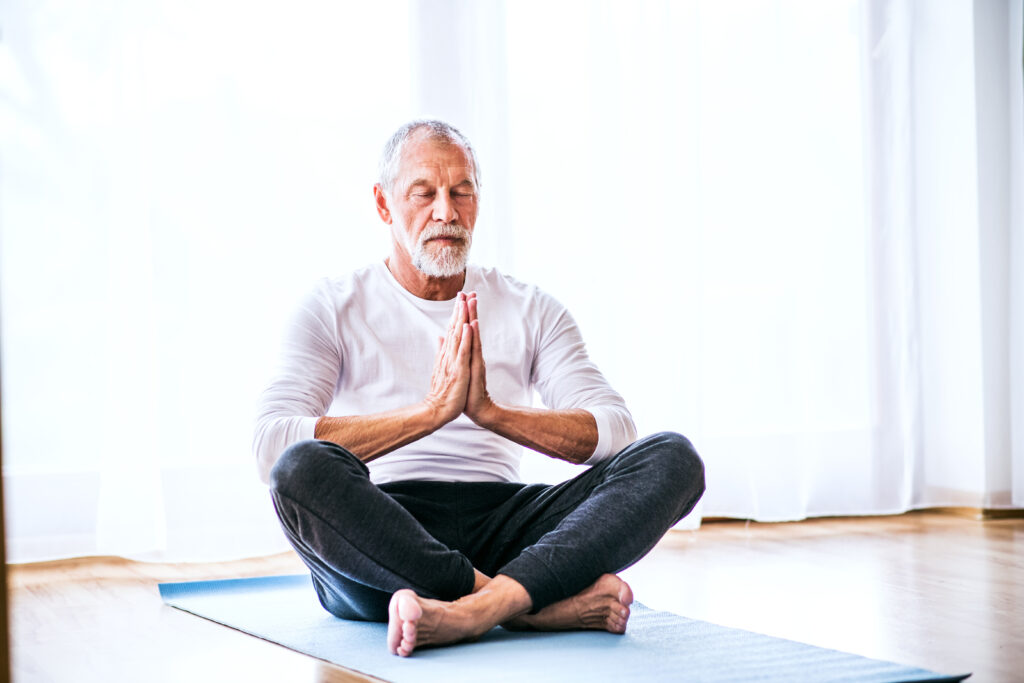 A contented senior man meditating at home.
